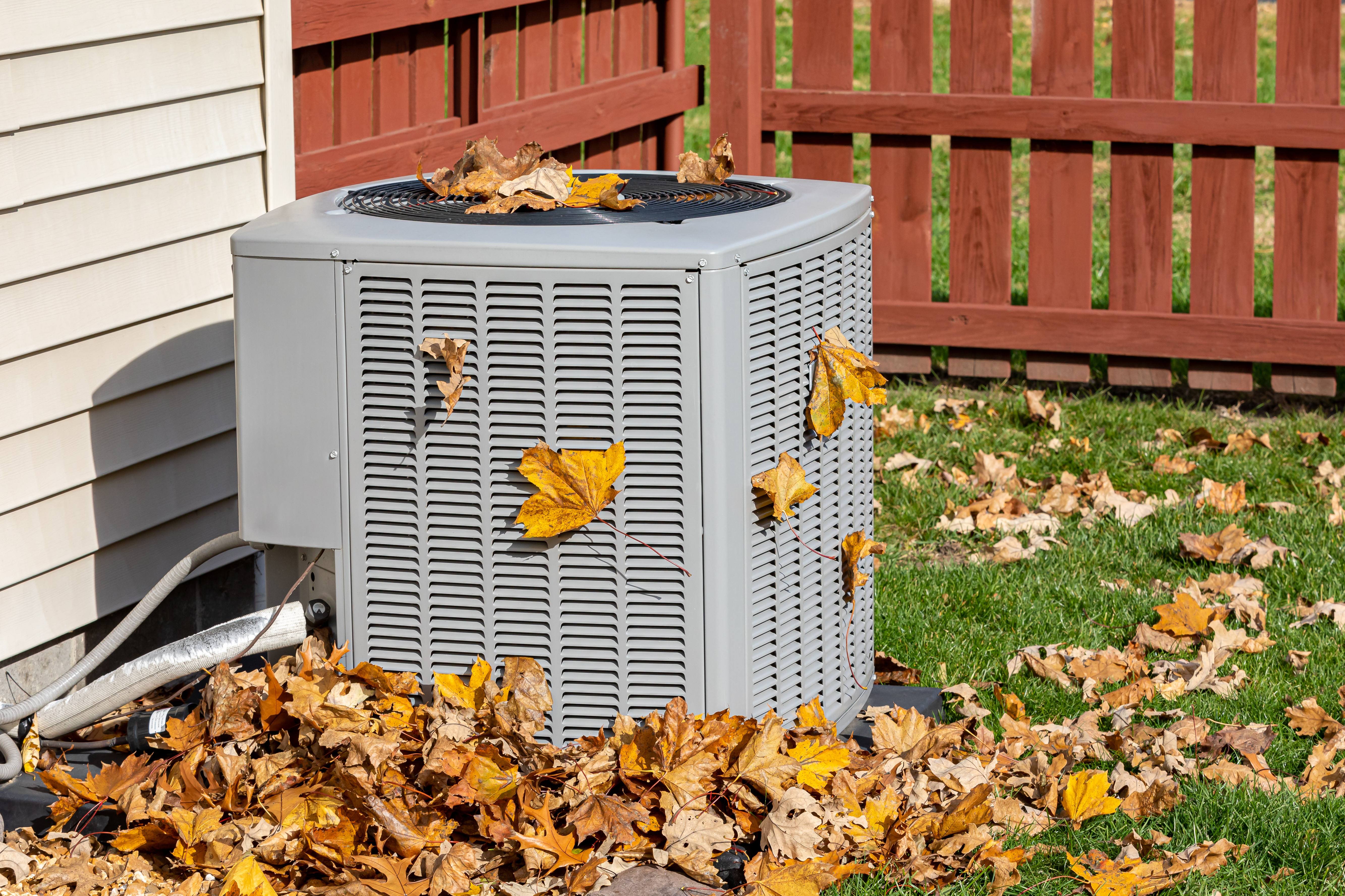 AC unit surrounded by fallen leaves